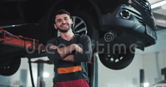 在一个现代化的汽车服务中心里一个穿着制服的大机械师微笑着他穿着制服直视着视频的预览图