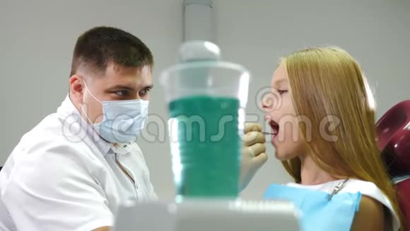 儿童病人坐在儿科牙医办公室的牙科椅上儿童牙科医生用口腔镜检查牙齿视频的预览图