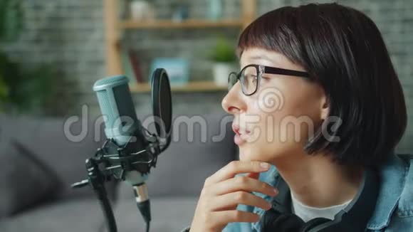 一位戴眼镜的漂亮女孩的特写镜头单独用麦克风录制音频讲话视频的预览图