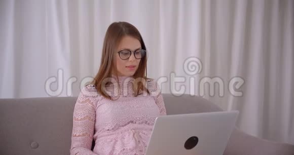 年轻有魅力的白种人女性在笔记本电脑上播放视频兴奋地坐在电脑上大笑视频的预览图