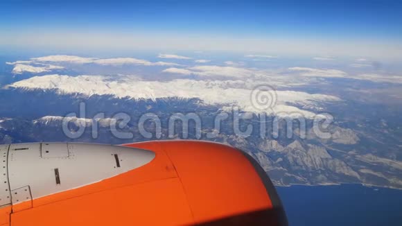 橙色的飞机飞过覆盖着雪和地中海的土耳其山脉从飞机窗口15可以看到视频的预览图