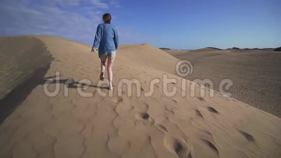 日落时一个女人跑过一片美丽的沙漠加那群岛视频的预览图