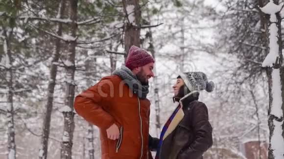 年轻可爱的时髦夫妇在森林里的雪下自拍照片博客作者用智能手机摄像头拍摄视频的预览图