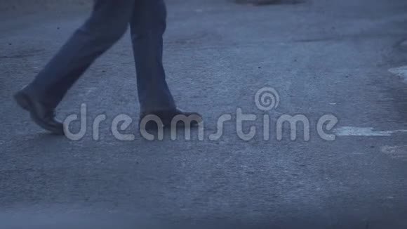 一个穿牛仔裤和黑鞋的人穿过马路视频的预览图