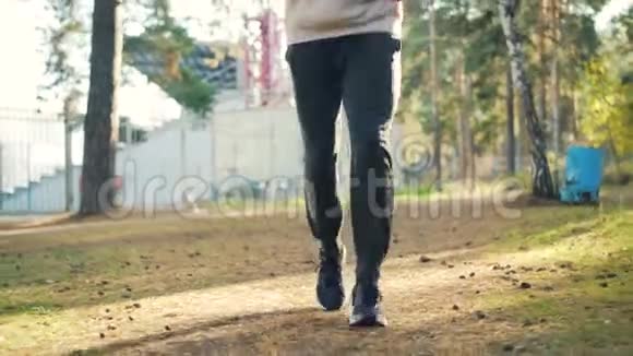 穿着运动鞋和运动服的帅哥戴着耳机在公园慢跑享受体育活动视频的预览图