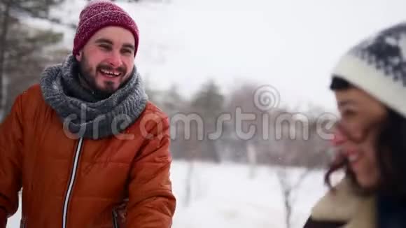 年轻可爱的一对夫妇在下雪的公园里散步男人牵着他的女朋友的手享受冬天的雪视频的预览图
