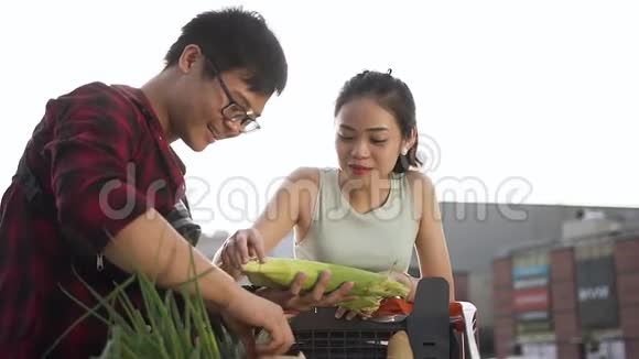 快乐快乐的亚洲夫妇详细检查他们车里的所有食物在大型超市附近购买产品视频的预览图