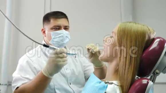 牙科诊所和牙齿保健概念十来岁的金发女孩在接受牙科治疗男性牙医视频的预览图