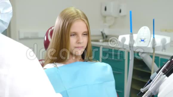 儿童牙科及牙科治疗理念戴牙椅的十岁女孩手中有医生的男性牙医视频的预览图