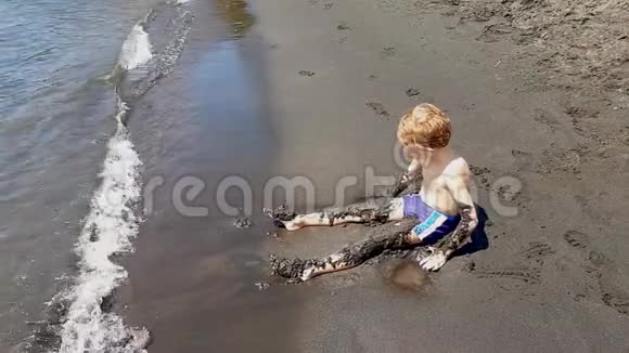 小男孩在岸上玩黑沙视频的预览图