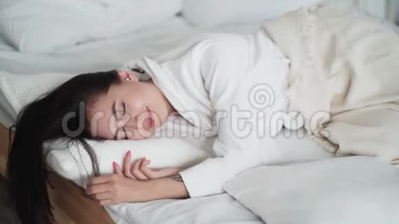 美丽的女人睡着的肖像早上醒来躺在床上微笑着视频的预览图