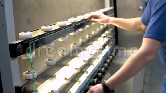 工人从传送带上拿一片玻璃用于生产和加工平板玻璃的传送带视频的预览图