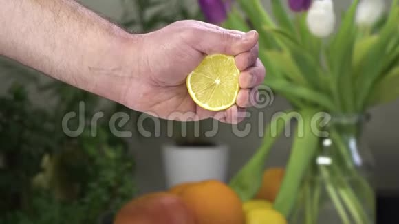 男性用一只手捏柠檬背景上有水果和植物视频的预览图