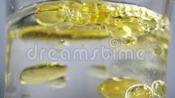 黄球泡在水里油倒入盛有水的容器中产生黄色气泡一杯酒视频的预览图