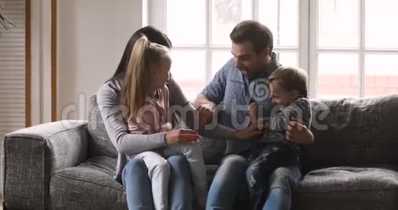 快乐的父母和小孩子在沙发上打痒视频的预览图