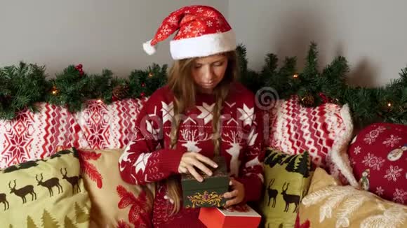 圣诞帽中悲伤而不快乐的女孩在新年装饰中打开圣诞礼盒视频的预览图