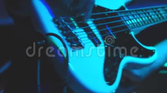 一个男人在舞台上弹低音吉他手工特写视频的预览图