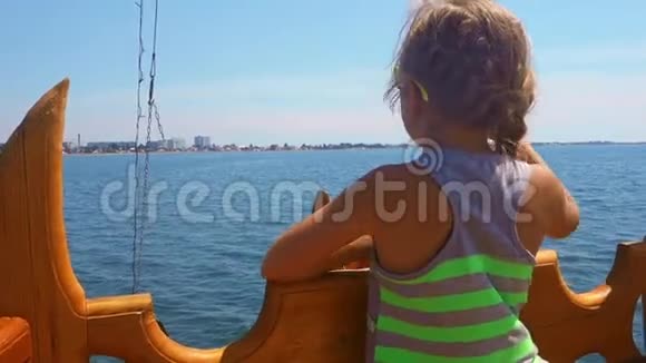 可爱的小女孩在海上坐船戴太阳镜的少女从船上看着城市少女视频的预览图