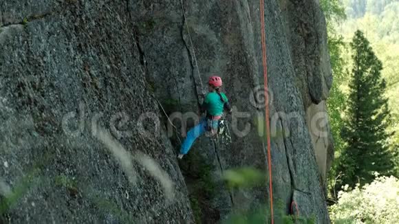 一个年轻的女人用绳子从悬崖上下来视频的预览图