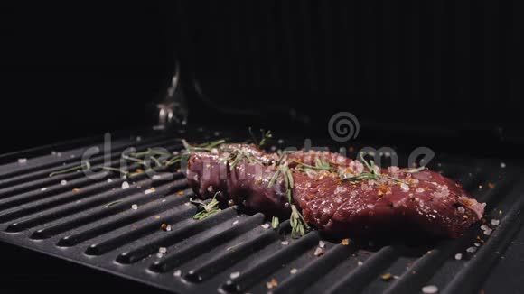美味多汁的肉排在烤架上烹制优质鲜烤把牛肉扔到电烤炉上倒入盐迷迭香视频的预览图