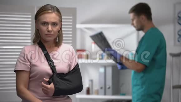 手臂悬吊的女性看镜头放射科医生检查骨x射线视频的预览图