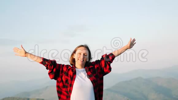 年轻迷人的白种人黑发女子站在山顶微笑着与山景的背景Fema视频的预览图