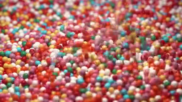 五颜六色的糖糖落在桌子上多种颜色的悬垂物落入五颜六色的球中红蓝绿色视频的预览图
