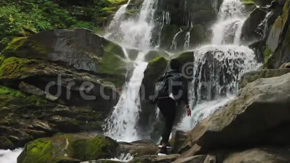 女游客正在观看高高耸立在石头上的瀑布视频的预览图