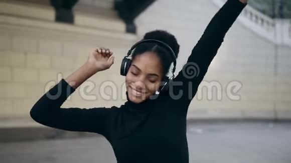 开朗的非洲女孩快乐的微笑令人叹为观止的非洲女人皮肤浅棕色戴着耳机放松慢慢跳舞视频的预览图