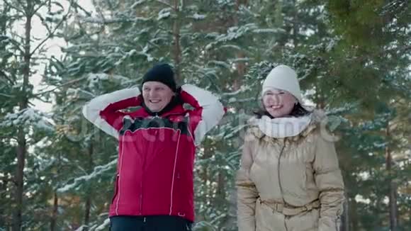 欢快的情侣在冬日的森林里笑着雪树上的风景快乐的男人和女人在雪地森林里玩得开心视频的预览图