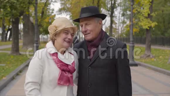 成熟的库卡西亚夫妇穿着优雅的衣服站在秋天的公园里说话妻子亲吻她可爱的丈夫视频的预览图
