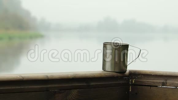一个带着热饮的老式杯子站在露台上的栏杆上背景是一个雾蒙蒙的秋天早晨视频的预览图