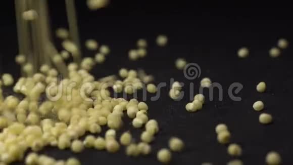 黄色小米倒在黑色背景的厨房黑色旋转桌上小米烹饪的美丽画面视频的预览图