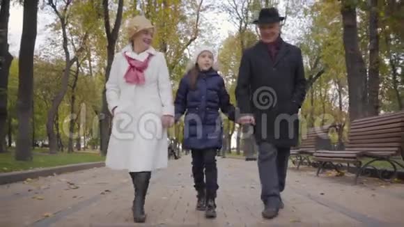 戴着白帽子的白人女孩和她的祖父母一起向前跑成熟夫妇的积极支出视频的预览图