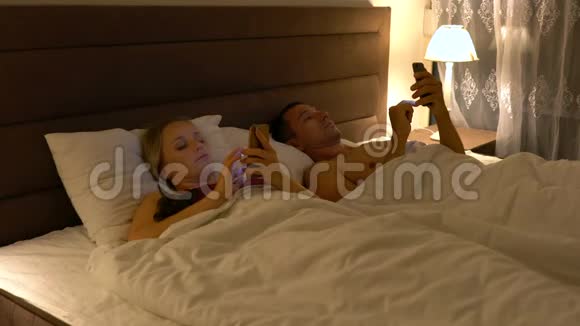 情侣躺在床上使用智能手机视频的预览图