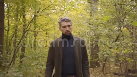 一个自信的白人男人在森林里走到镜头前揉着手检查时间成人视频的预览图