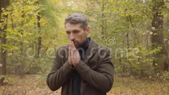 一个英俊的白人男子的特写灰色的头发站在森林里穿着便装的家伙手里视频的预览图