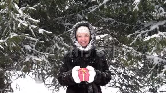 手拿红色圣诞礼盒的冬装快乐微笑的女人视频的预览图