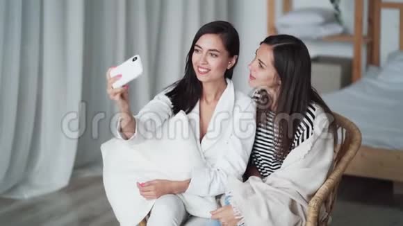 两个女孩在电话里自拍摆姿势展示和平的姿态在家微笑视频的预览图