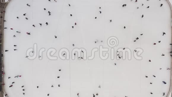 空中拍摄的人们骑着冬天的冰场在冰上滑行市中心冬季冰场的俯视图视频的预览图
