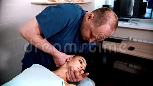 脊椎按摩治疗医生专家给一个女性病人一个温和的颈部按摩弯曲颈部到视频的预览图