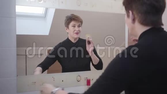 高雅的高加索女人的画像看着大镜子用脸粉时尚成熟女士视频的预览图