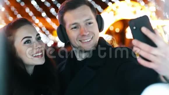 两对浪漫情侣在户外圣诞树上自拍情侣接吻的肖像视频的预览图