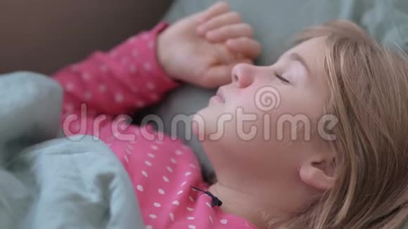 一个发烧的小女孩和一个女人的手抚摸她肖像母亲照顾生病的孩子躺在床上视频的预览图