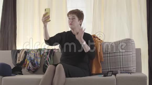 美丽的高加索高级女士在她的智能手机上录制自拍视频的肖像成熟的女性博客作者视频的预览图