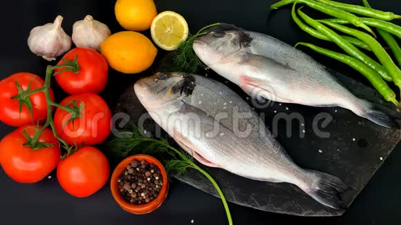 柠檬西红柿辣椒两具新鲜的生海鱼和一枝鳃放在黑色上视频的预览图
