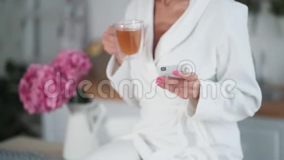 关门女人手拿着杯茶用电话在家里发信息视频的预览图