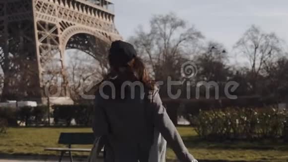 镜头跟随美丽快乐的旅游女人向埃菲尔铁塔跑去回头微笑着看着镜头缓慢的动作视频的预览图