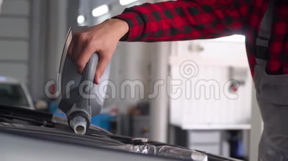 修理汽车修理店修理一辆汽车的人机械师把油倒进发动机视频的预览图