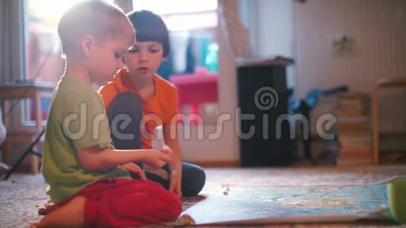 两个男孩在地板上玩棋盘游戏视频的预览图